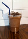 Iced chocolate topped with chocolate chunk in takeaway glass isolated on wooden table