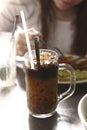 Iced coffee with ice milk and straw in glass mug