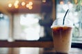 Iced coffee latte summer refreshing drink in take away plastic cup  on wood table with blurred bokeh coffee shop background Royalty Free Stock Photo