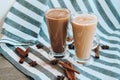 Iced coffee with milk in tall glasses, Cups of tasty frappe coffee, Latte machiato, two cups of cappuccino with cinnamon sticks