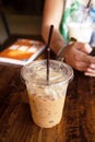 Iced coffee in a plastic cup with straw on a wooden table. Royalty Free Stock Photo