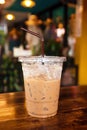 Iced coffee in a plastic cup with straw on a wooden table. Royalty Free Stock Photo