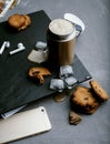Iced coffee in a steel thermo mug, with almond milk, ice cubes and homemade cookies on a black stone background. Cold summer drink Royalty Free Stock Photo