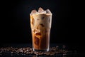 Iced coffee with swirling milk in a glass, coffee beans scattered