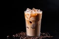 Iced coffee with swirling milk in a glass, coffee beans scattered