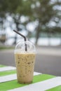 Iced coffee in takeaway cap on wooden table,blurred sea in background,selective focus.