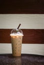 Iced coffee in takeaway cup on marble table with blurred two tone wooden in background,Selective focus,filtered image, dark Royalty Free Stock Photo