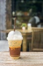 Iced coffee in takeaway cup on wood table with blurred coffee cafe background, selective focus Royalty Free Stock Photo