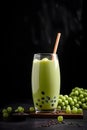 Iced green bubble milk tea with coffee tapioca pearls and green jelly bubble tea balls in high glass with a straw in dark