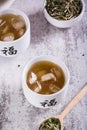 Iced green japanese hojicha tea in cups and leaves in a bowl on the table vertical view Royalty Free Stock Photo