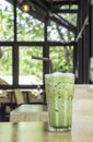 Iced green tea  in glass on the wooden table Background glass windows and  tree Royalty Free Stock Photo