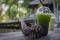 Iced green tea honey lemon drink with dried pine cones on wooden table against old wood house background Royalty Free Stock Photo