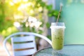 Iced green tea matcha latte with milk on table and chair against nature garden background Royalty Free Stock Photo