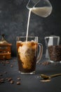Iced latte coffee in cup glass with pouring milk on black Royalty Free Stock Photo