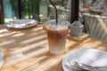 iced latte coffee, showing separate in a layer the bottom as milk top by coffee shot in a tall plastic glass on a wooden table