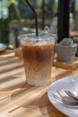 Iced latte coffee, showing separate in a layer the bottom as milk top by coffee shot in a tall plastic glass on a wooden table
