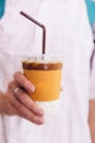 Iced latte in paper wrap plastic cup with straw that held by a man hand Royalty Free Stock Photo