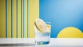 Iced Lemon Water in Glass with Slice on Blue and Yellow Background. Royalty Free Stock Photo