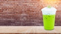 Iced matcha green tea latte frappuccino with milk foam in takeaway cup on wooden table, Summer drinks with iced