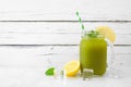 Iced matcha lemonade in a mason jar glass against white wood