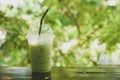 Iced milk green tea on wooden table with green nature background Royalty Free Stock Photo