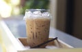 Iced milk tea in plastic glass, put on the wooden floor, behind it is a green garden Royalty Free Stock Photo