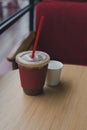 Iced mocha and drinking water in a paper cup on a wooden table in a certain caf