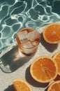 An iced orange cocktail beside fresh citrus slices, poolside on a sunny day