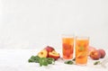 Iced peach tea or cocktail with mint and lobdom,recipe for refreshing summer drink.Two glasses with peach fruit lemonade on light Royalty Free Stock Photo