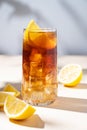 Iced tea with lemon and ice in a tall glass on a yellow background with shadow. The concept of a refreshing drink or lemonade on a Royalty Free Stock Photo