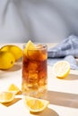 Iced tea with lemon and ice in a tall glass on a yellow background with shadow and fruits. The concept of a refreshing drink or Royalty Free Stock Photo