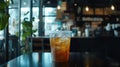 Iced Tea in Plastic Cup on Table in Cafe with Plants and Soft Lighting Royalty Free Stock Photo