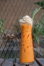 Iced Thai tea with whipped cream set on the table ready to serve. Royalty Free Stock Photo