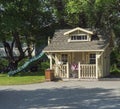 Iceland, Hveragerdi, August 5, 2019: Big cute wooden children house on garden with slide for the children`s games, pink pram and