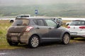 Extremely dirty Suzuki Swift 4x4 small car on an Iceland road after driving on typical muddy roads in rain