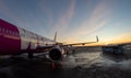 Passengers boarding Plane reflecting sunset colors next to bus