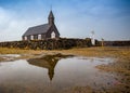 Icelandic style church with stone wall reflects in puddle Royalty Free Stock Photo