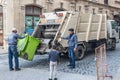 Garbage collection service, A waste collector working on emptying garbage cans for garbage collection with waste loading on a truc