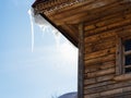 icicle illuminated by sun on roof of old log house