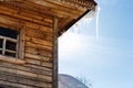 icicle illuminated by sun on roof of wooden house