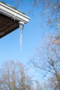 An icicle on  roof  corner on clear sunny winter day against blu Royalty Free Stock Photo