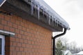 Icicles on the eaves of the roof of a brick house, temperature drop. The melt water gradually flows down Royalty Free Stock Photo