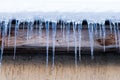 Icicles hang on a house roof. Snow melt from house roof warm winter day Royalty Free Stock Photo