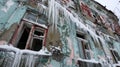 Icicles hang precariously from the shattered windows of a deserted house its walls sagging under the weight of