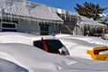 Row of icicles hang from a building and cars buried in the snow