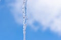 Icicles hang on the roof of a house against a bright blue sky. Spring landscape with icicles hanging from the roof of the house. Royalty Free Stock Photo