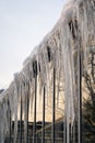 Icicles hang from roof and wall in winter. Frozen water from melting ice and snow during spring thaw