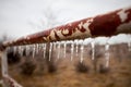 Icicles hanging from an old rusty rural pole