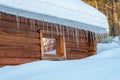 Icicles hanging from the roof of the house. Melting snow on the roof. Dangerous sharp transparent icicles hanging on the