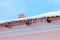 Icicles hanging on the roof of a pink building. Nice warm and Sunny weather